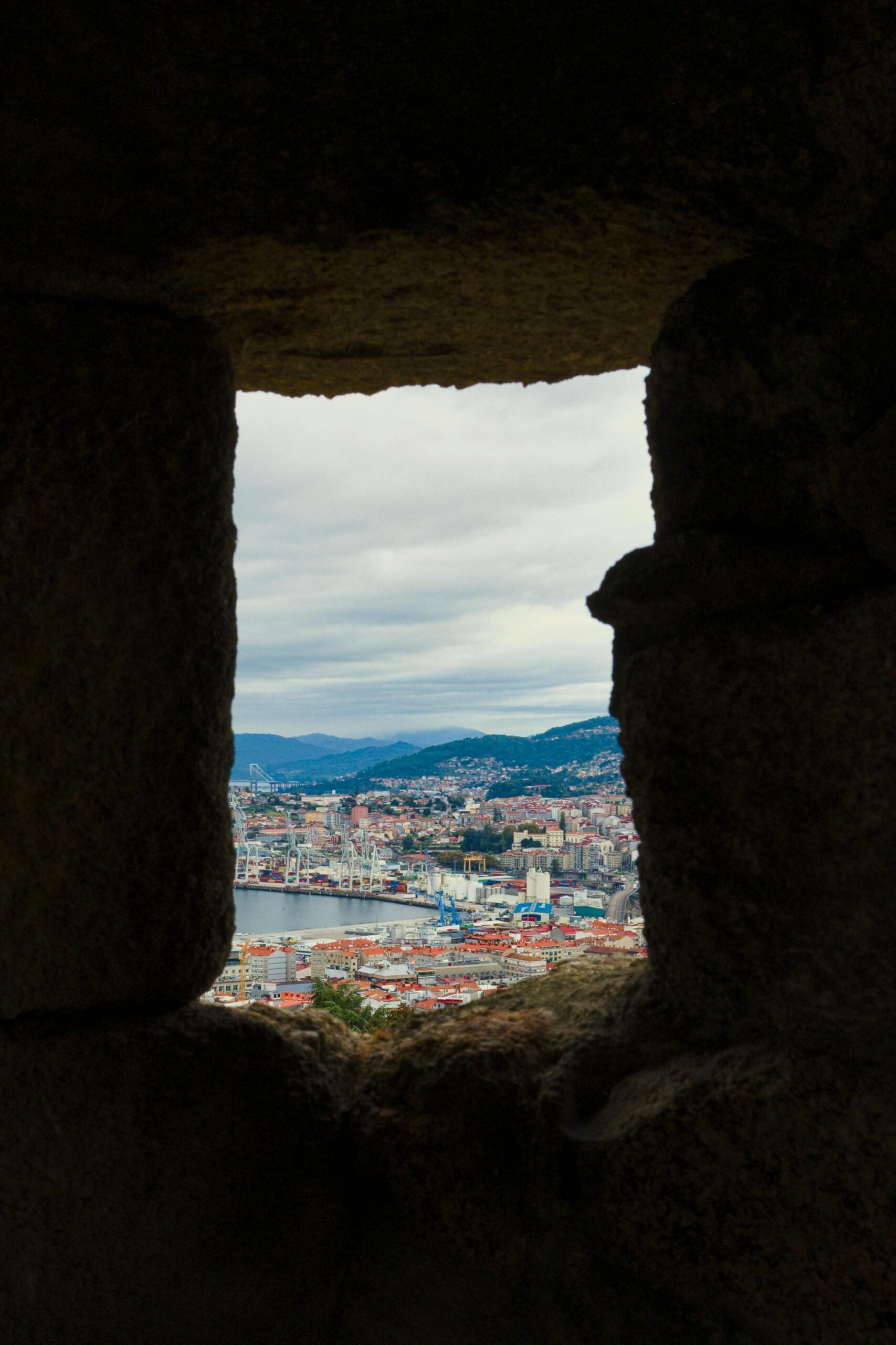Scenic view of Vigo, Spain through a historic stone window. Urban landscape with coastal cityscape.